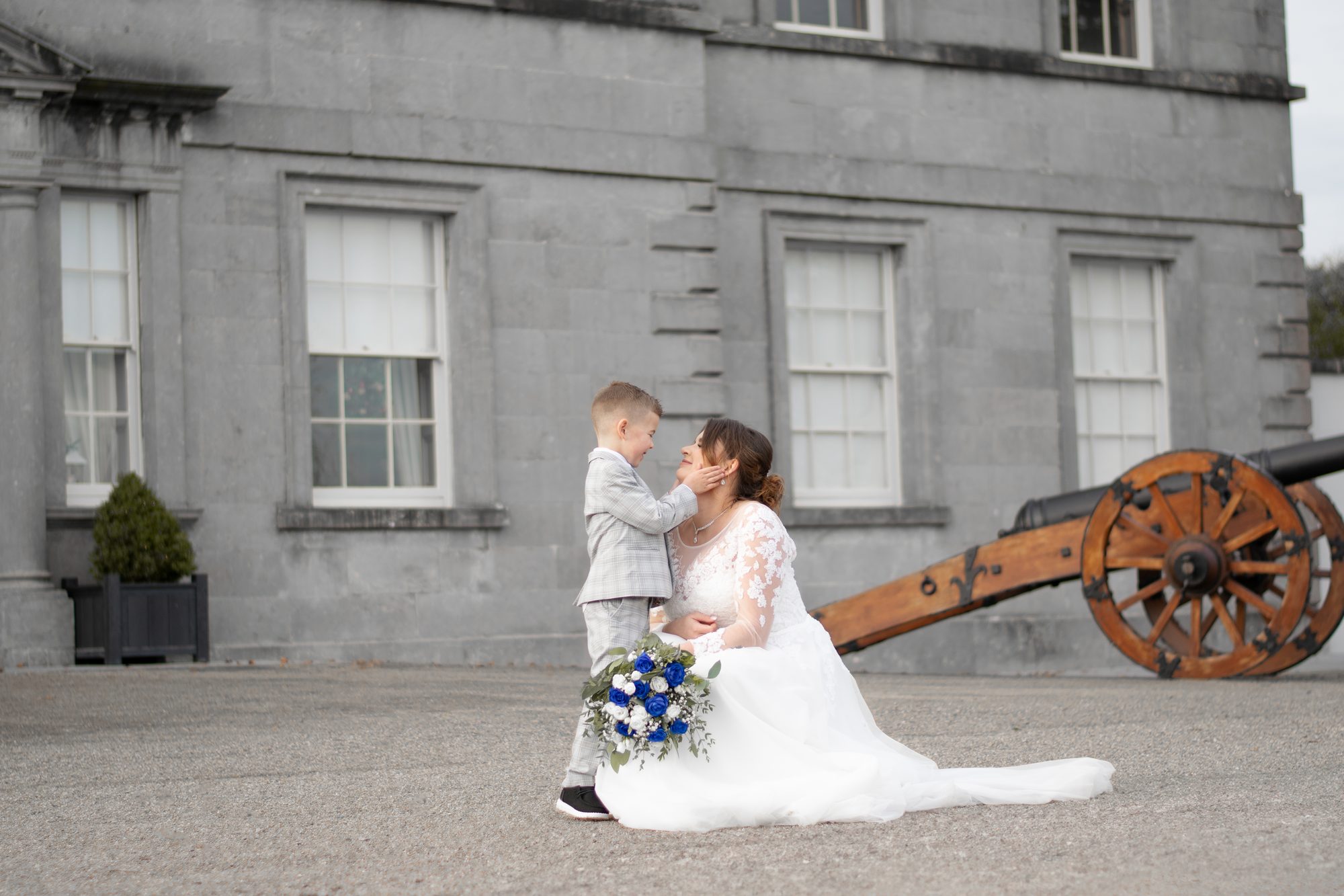 A groom lifting his bride in front of a historic manor house