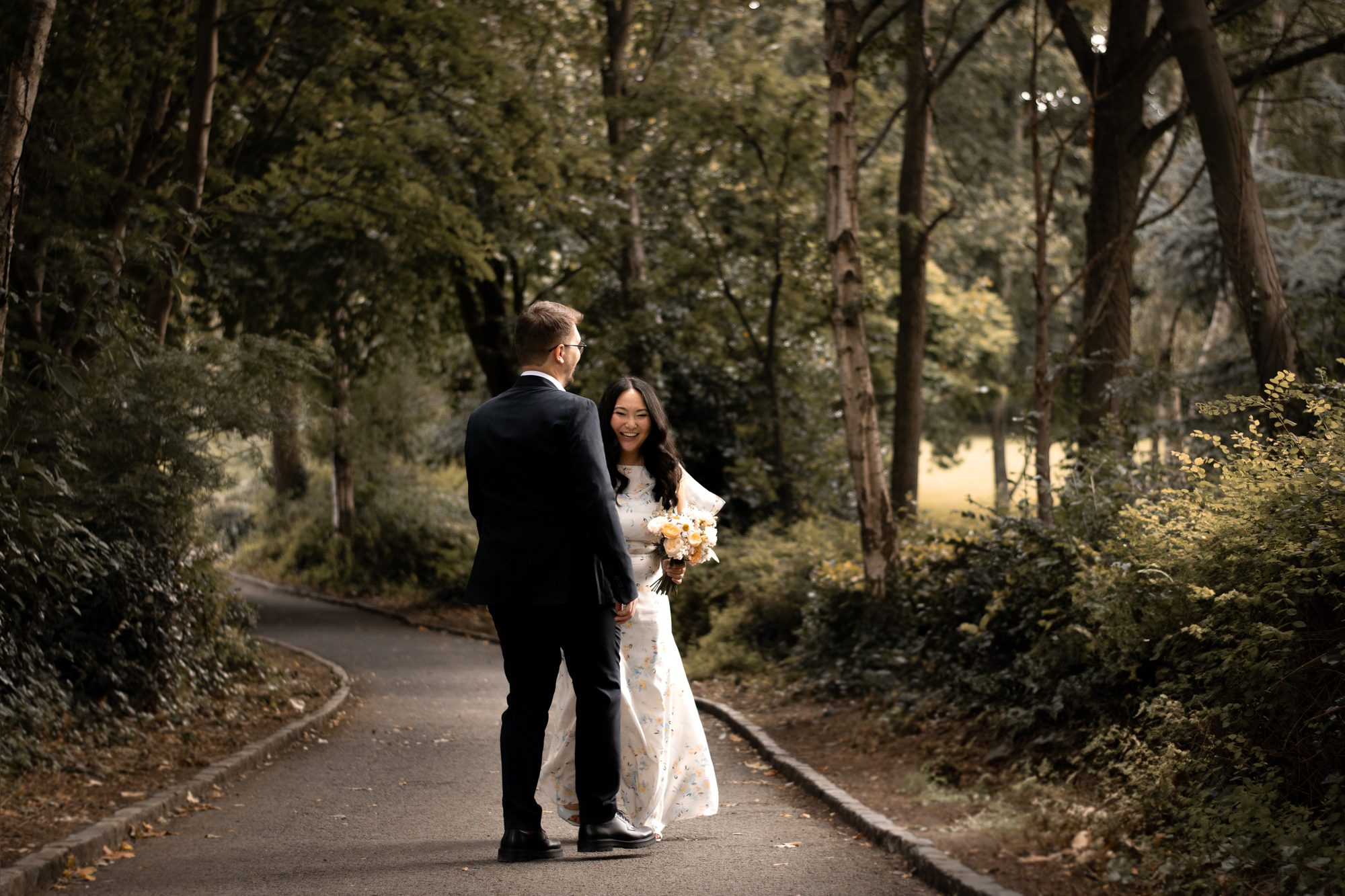 A bride and groom walking together along a woodland path
